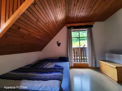 a attic room with a bed and a window at Apartments Cesar in Bohinj