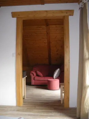 a living room with a red couch under a wooden ceiling at Apartments Cesar in Bohinj