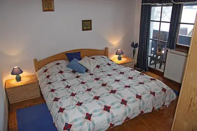 a bedroom with a bed with a quilt on it at Apartments Cesar in Bohinj
