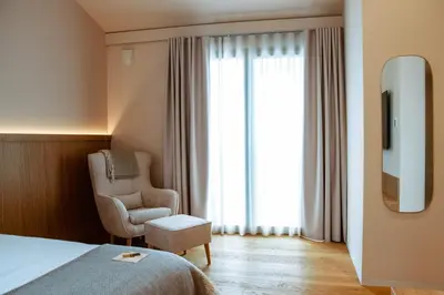 a hotel room with a bed and a chair and a window at Posestvo Ščurek wine in Dobrovo