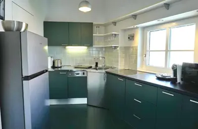 a kitchen with green cabinets and a white refrigerator at Poet Apartment in Ljubljana