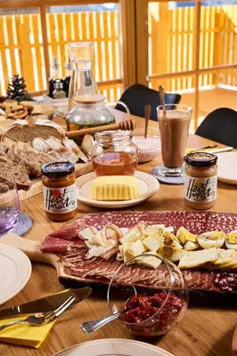a wooden table topped with plates of cheese and other foods at Cottage Osojnik - Alpine escape with Wellness in Solčava