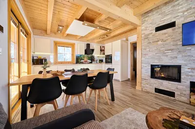 a kitchen and living room with a table and a fireplace at Cottage Osojnik - Alpine escape with Wellness in Solčava