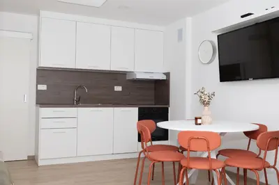 a kitchen with white cabinets and a table with orange chairs at Apartment Lucka, Kranjska Gora in Kranjska Gora
