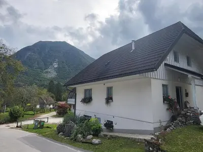 a white house with a mountain in the background at Apartment Luka at Soča & Koritnica confluence in Bovec