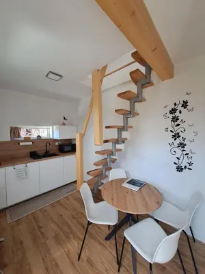 a kitchen and dining room with a wooden table and stairs at Bella Apartment in Žirovnica