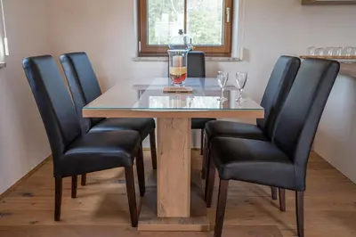 a dining room table with black leather chairs and a glass at Nedelkova Zidanca in Trnovska Vas