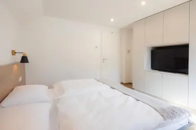 a white room with a bed and a flat screen tv at Apartments BB in Bohinj