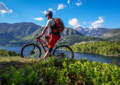 a man riding a bike on a hill near a lake at Apartments BB in Bohinj