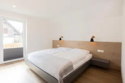 a bedroom with a large bed with a large window at Apartments BB in Bohinj