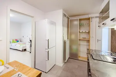 a kitchen with a refrigerator and a room with a bed at Cute tiny house in Ljubljana