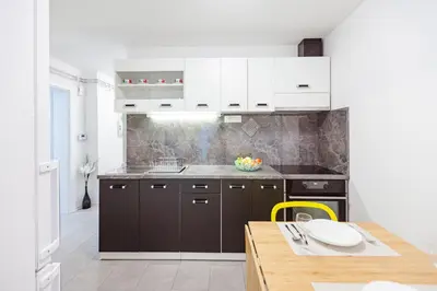 a kitchen with white cabinets and a wooden table at Cute tiny house in Ljubljana
