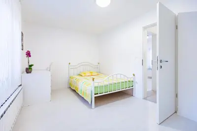 a white bedroom with a bed and a white floor at Cute tiny house in Ljubljana