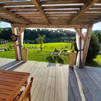 a wooden deck with benches and a view of a field at Počitniška hiška pri Lipi in Dramlje