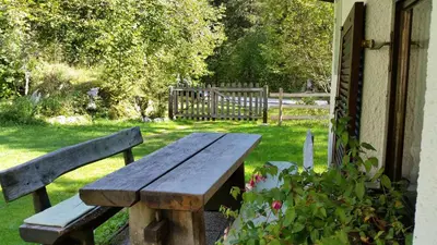 a wooden bench sitting in the grass next to a house at Počitniška hiša Ukanc in Bohinj
