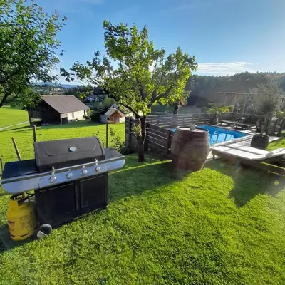 a barbecue grill sitting in the grass next to a pool at Glamping pod Hrastom in Dramlje