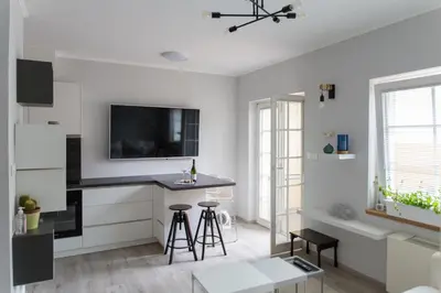 a white kitchen with a black counter and stools at Bled Center modern apartment with big balcony in Bled