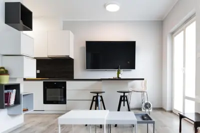a kitchen with white cabinets and a tv on the wall at Bled Center modern apartment with big balcony in Bled