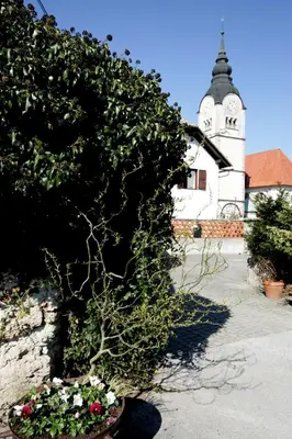 a plant in a pot next to a building with a clock tower at Resort Vidmar - Baroque villa near Bled in Lesce