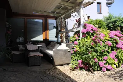 a patio with a couch and some pink flowers at Apartment Baci for 4 guests in Ljubljana