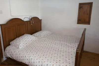 a bed with a wooden headboard in a bedroom at Dormouse House in Slovenia in Grahovo