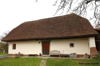 a large white house with a thatched roof at Dormouse House in Slovenia in Grahovo