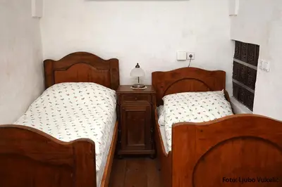 two twin beds in a room with a night stand at Dormouse House in Slovenia in Grahovo