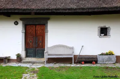 a white house with a bench and a door at Dormouse House in Slovenia in Grahovo