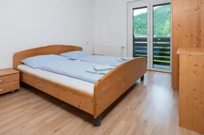 a wooden bed in a room with a window at Apartments Žnidar in Bohinj