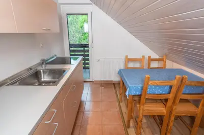 a kitchen with a sink and a table with chairs at Apartments Žnidar in Bohinj