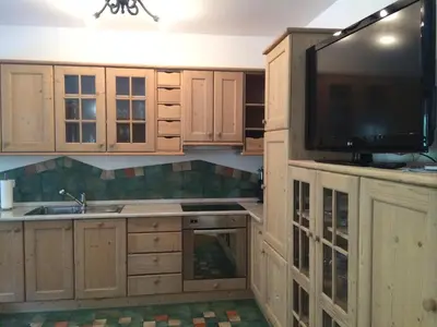 a kitchen with wooden cabinets and a flat screen tv at Apartments Pod macesnovo streho in Solčava