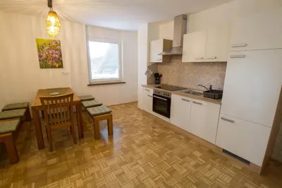 a kitchen with white cabinets and a table and chairs at Apartma pri Klari in Kočevje