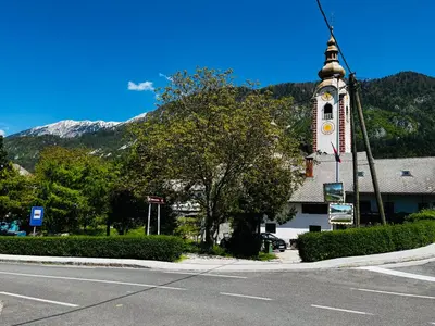 a church with a clock tower in front of a street at Apartma Jana in Žirovnica