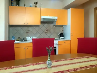 a kitchen with orange cabinets and a table with red chairs at Apartments Bogdanovic in Maribor