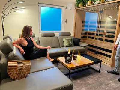 a woman sitting on a couch in a living room at JUNGLE Wellness Apartment in Trzin