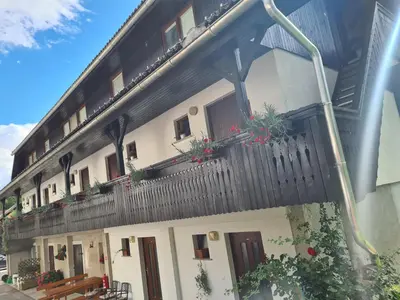 a building with a balcony with potted plants on it at Gostilna Batišt in Bohinjska Bela