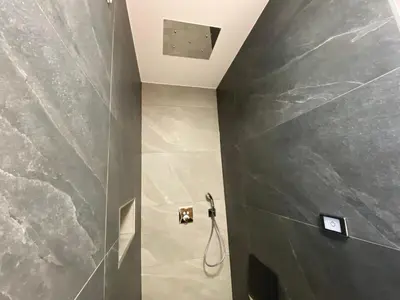 a bathroom with a shower with a gray wall at Apartma ROGATEC in Rogatec