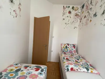 a room with a bed and a door with flowers on the wall at Apartma ROGATEC in Rogatec