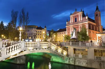 a bridge over a river in a city at night at Nick & Klaras Central Apartments in Ljubljana
