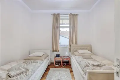 two beds in a room with a window at Nick & Klaras Central Apartments in Ljubljana