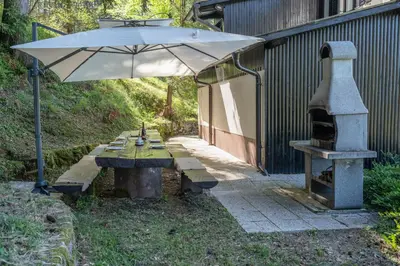 a picnic table with an umbrella and a stove at Hiška Gmajna in Slovenj Gradec
