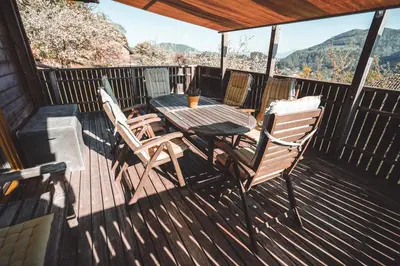 a wooden deck with a table and chairs on it at KAJZA KOLOVRAT in Mozirje