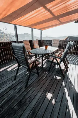 a wooden deck with a table and chairs on it at KAJZA KOLOVRAT in Mozirje