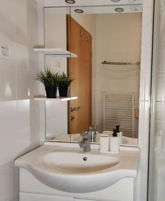 a white bathroom with a sink and a mirror at Apartment Marusa in Moravske Toplice