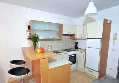 a kitchen with white cabinets and a wooden counter top at Apartment Marusa in Moravske Toplice