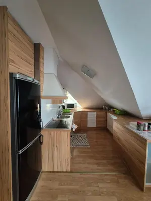 a kitchen with a black refrigerator and wooden cabinets at Oddih v mirnem in zelenem okolju in Škofljica