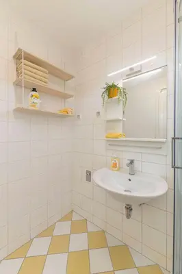 a white bathroom with a sink and a mirror at Cozy Garden Flat in Ljubljana