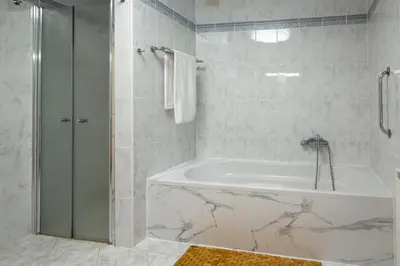 a white bathroom with a tub and a shower at Herga Wine Estate - Old lady - Holiday Home in Ivanjkovci
