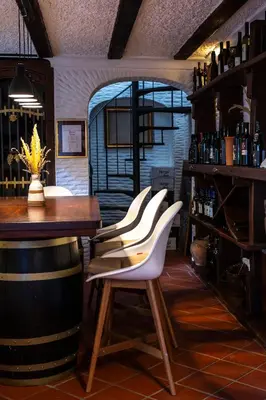 a bar with white chairs and a table and wine bottles at Herga Wine Estate - Nest above wine cellar - rooms in Ivanjkovci
