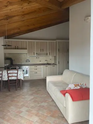 a living room with a white couch and a kitchen at Zarova Apartment with wine tasting experience in Kojsko